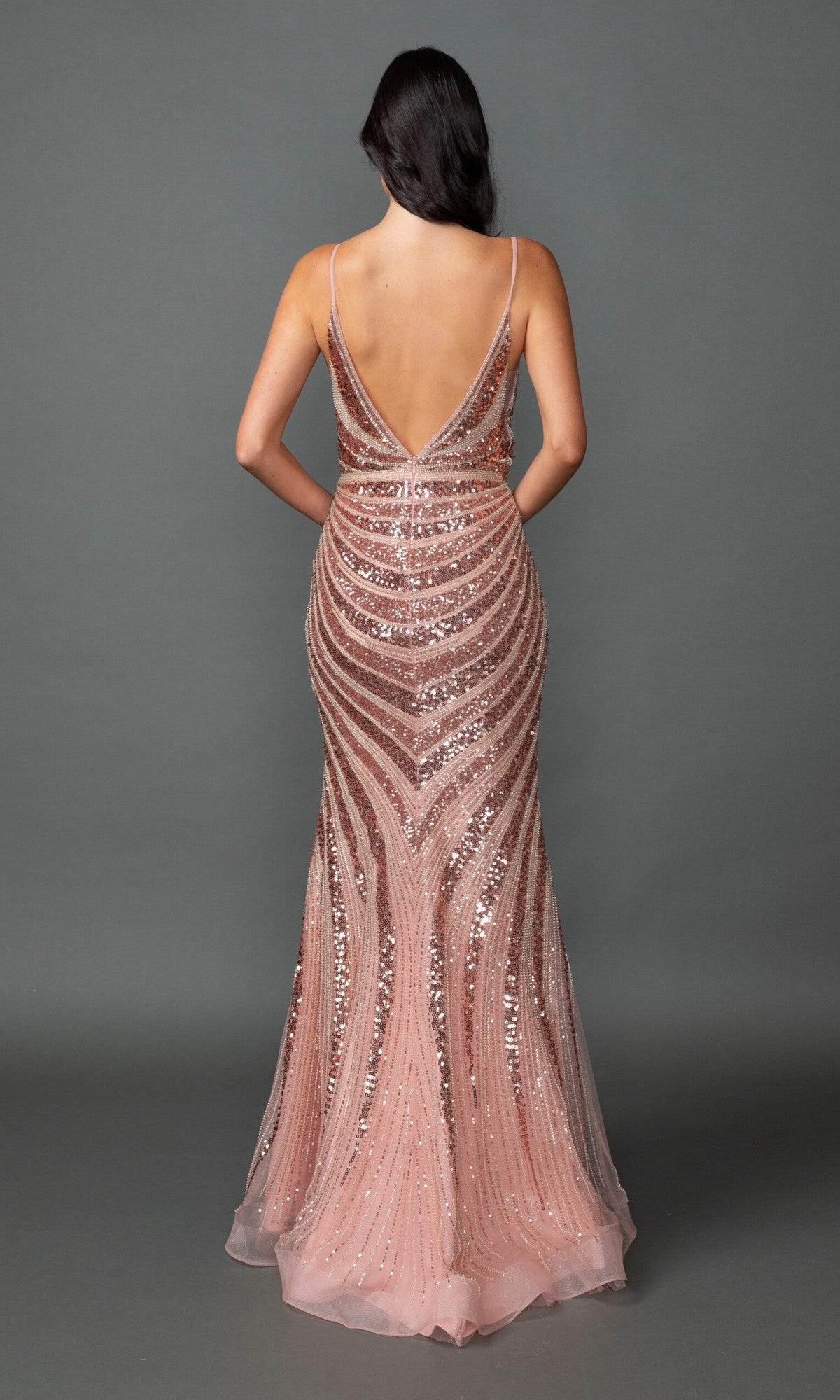 A woman models the Dancing Queen 4557, a sleeveless, floor-length rose gold sequin prom gown with a deep V-back, against a plain gray background.